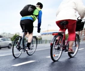 two bike riders one man on the left in bright blue and green shirt and a women wearing red pants and a white shirt